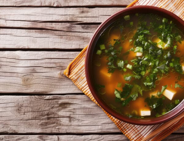 Miso Soup with Tofu and Chives. Traditional Japanese miso soup with soft tofu cubes and chopped chives in a rustic earthenware bowl, copy space.